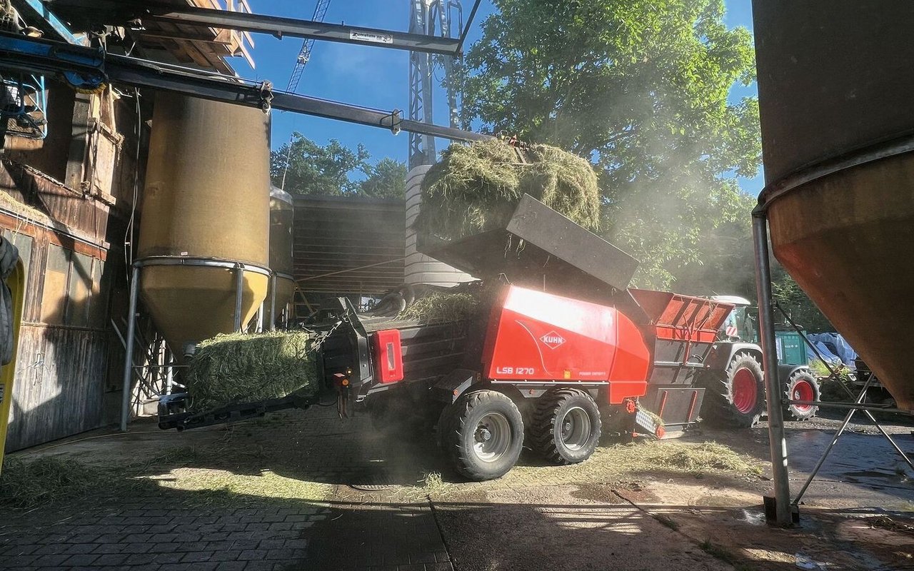 Eine Ballenpresse presst loses Heu aus dem Heustock zu Ballen.