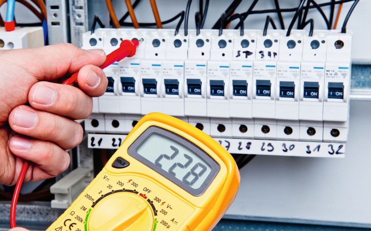 Ein Multimeter wird bei einem Sicherungskasten benutzt, um die Stromspannung zu messen.