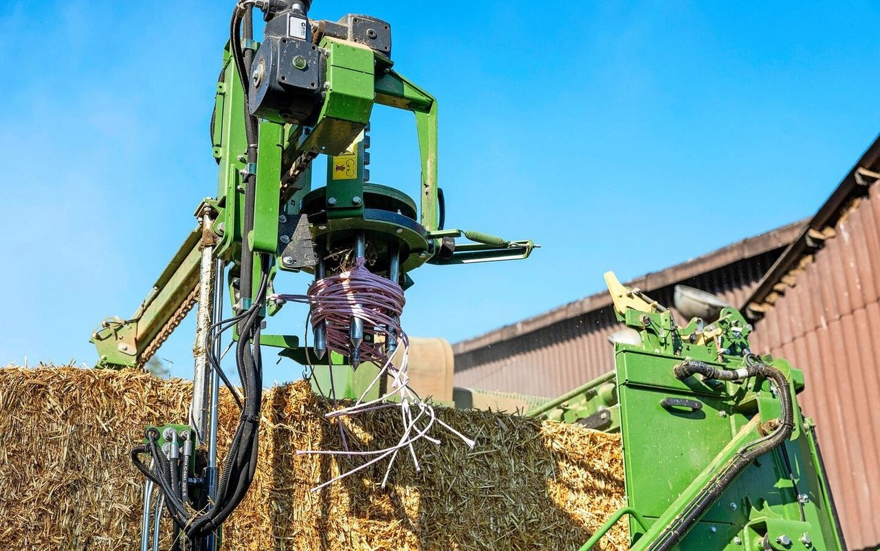 Die Quaderballen werden automatisch geöffnet. Die Ballenschnüre werden aufgewickelt und fallen in einen Container.  