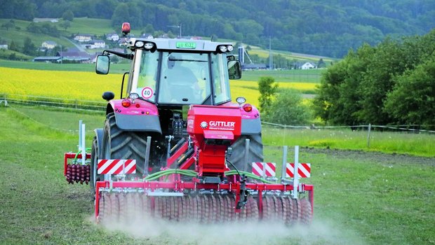 Traktor mit angehängter Sämaschine macht eine Übersaat auf einer Naturweide.