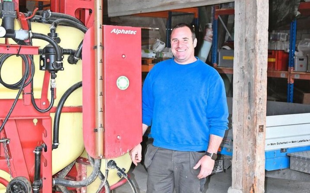 Patrik Huber steht fürs Foto gerne vor seine Feldspritze. Sie ist älteren Jahrgangs, aber modern ausgestattet.  